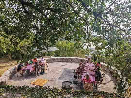 Private tour in village of Klinci, with group of people sitting around the table, enjoying the meal and panoramic views of Luštica.